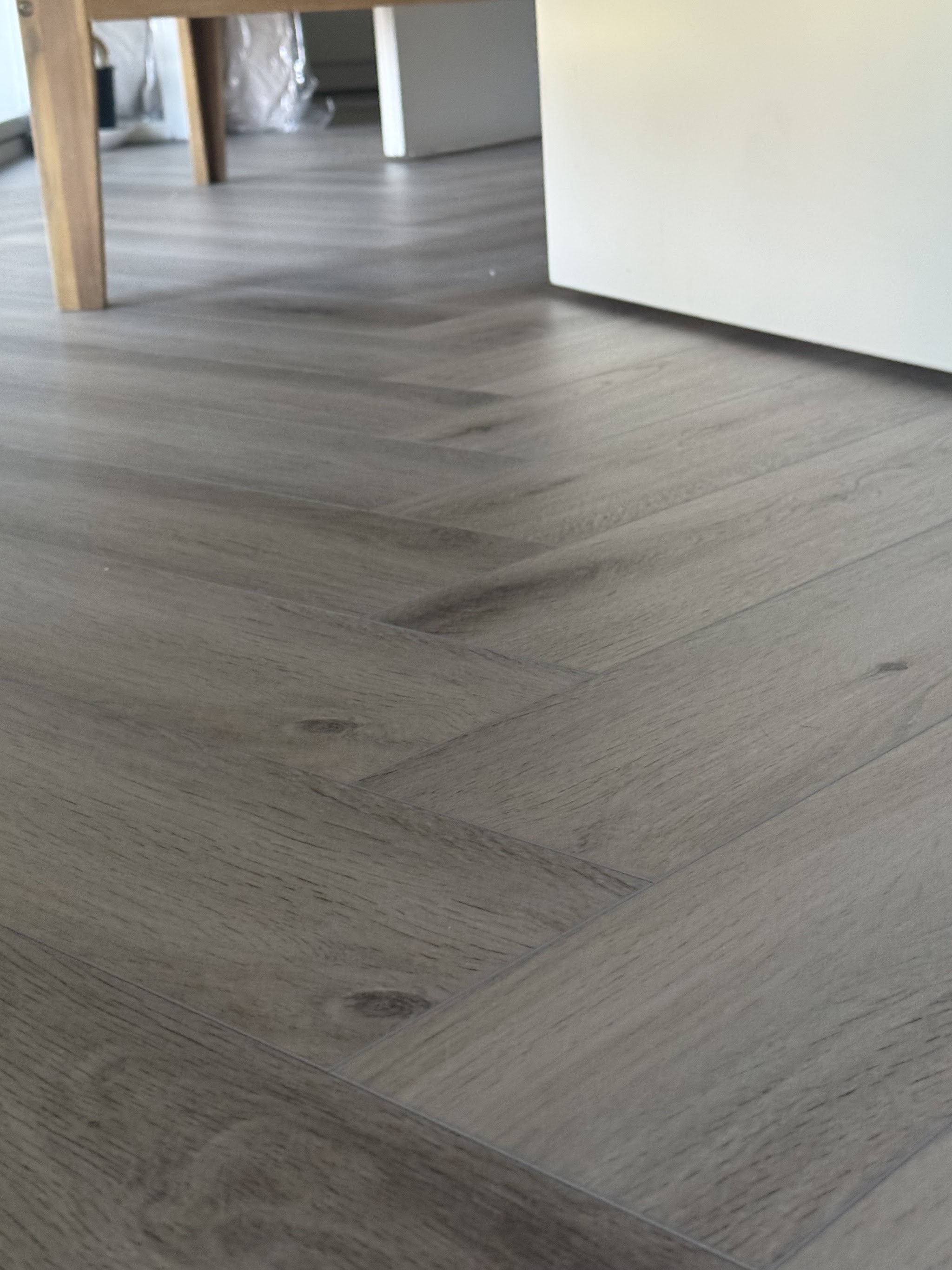 Visgraatvloer van dichtbij, met de poten van een eettafel