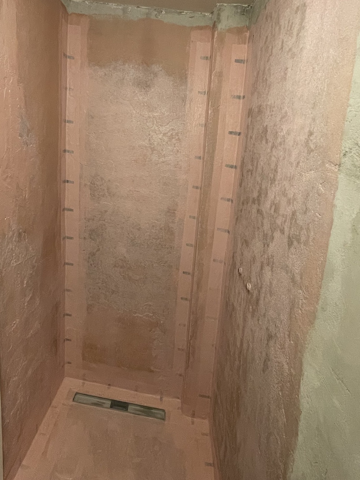 Gesloopte douche met een vloer op afschot en de douchegoot gezet, klaar voor het tegelwerk