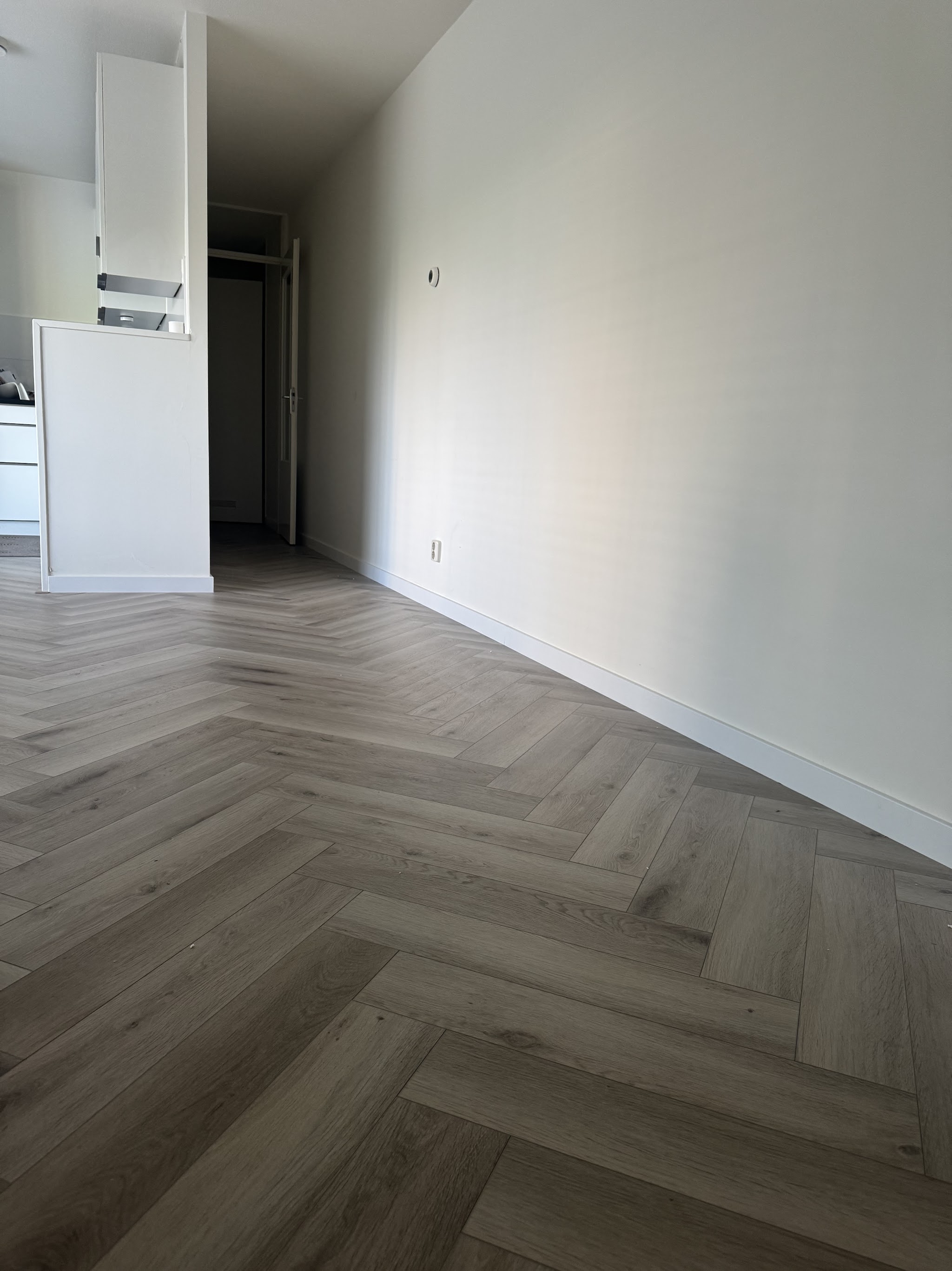Lege kamer met een lichte eiken visgraatvloer van wand tot wand